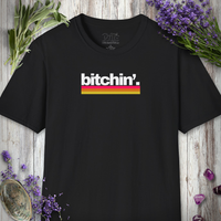 Unisex t-shirt printed with the word 'bitchin'.' in bold white letters above a pink-to-yellow retro gradient stripe.