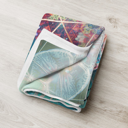 "Primordial Soup" throw blanket styled across a bed, showing size and drape.