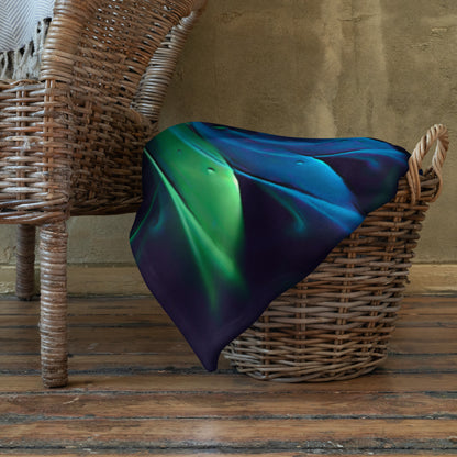 The "Awakened" throw blanket draped over a couch, corner folded to show the white reverse side